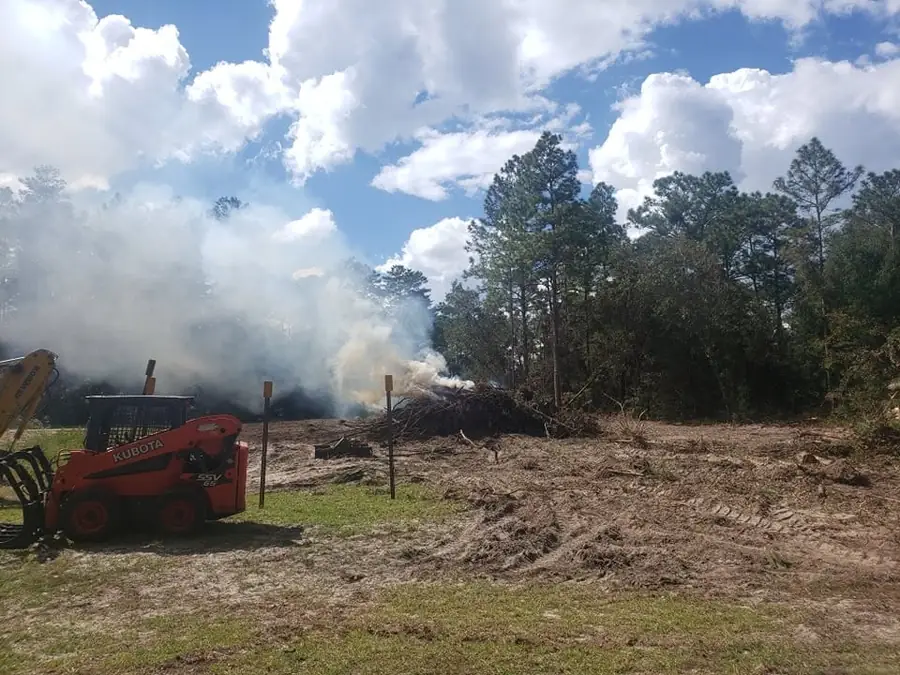 Kubota skid steer beside a burning brush pile on a cleared property near Ocala